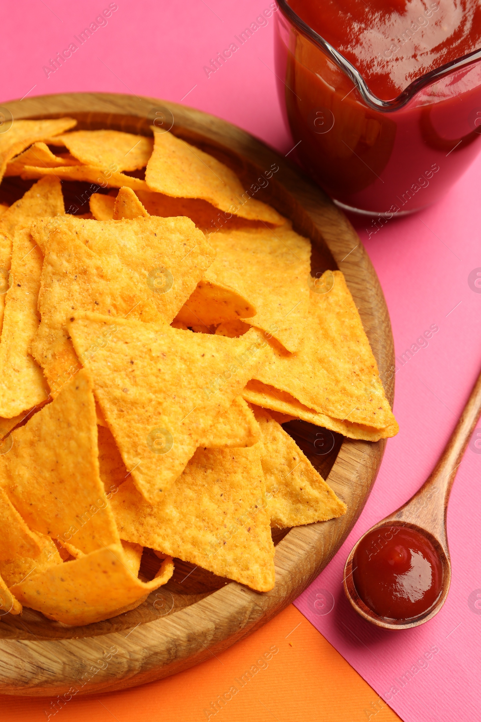 Photo of Tasty ketchup and nachos on color background, closeup