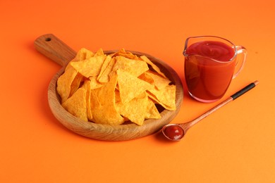 Photo of Tasty ketchup and nachos on orange background