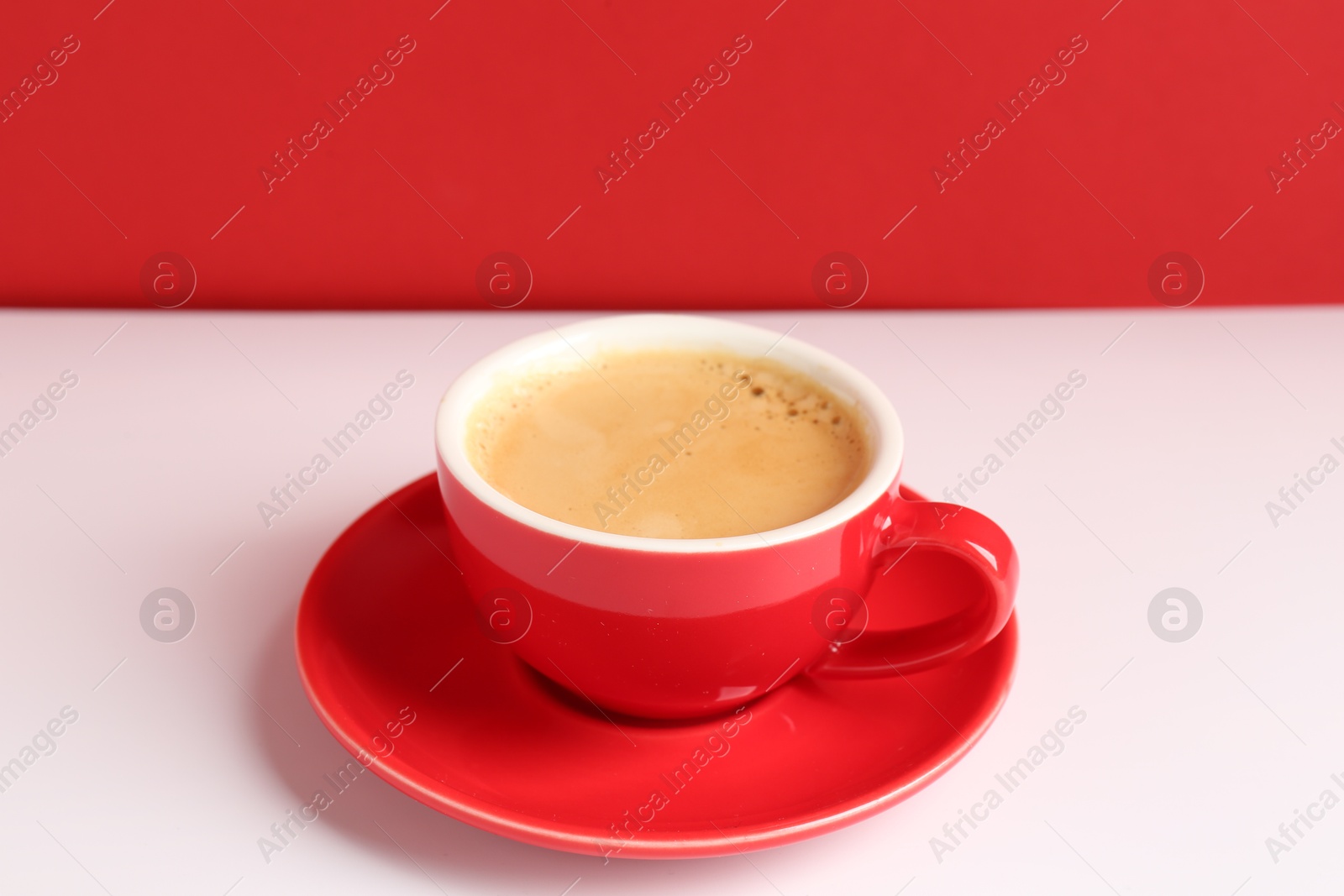 Photo of Red cup with coffee on white table, closeup