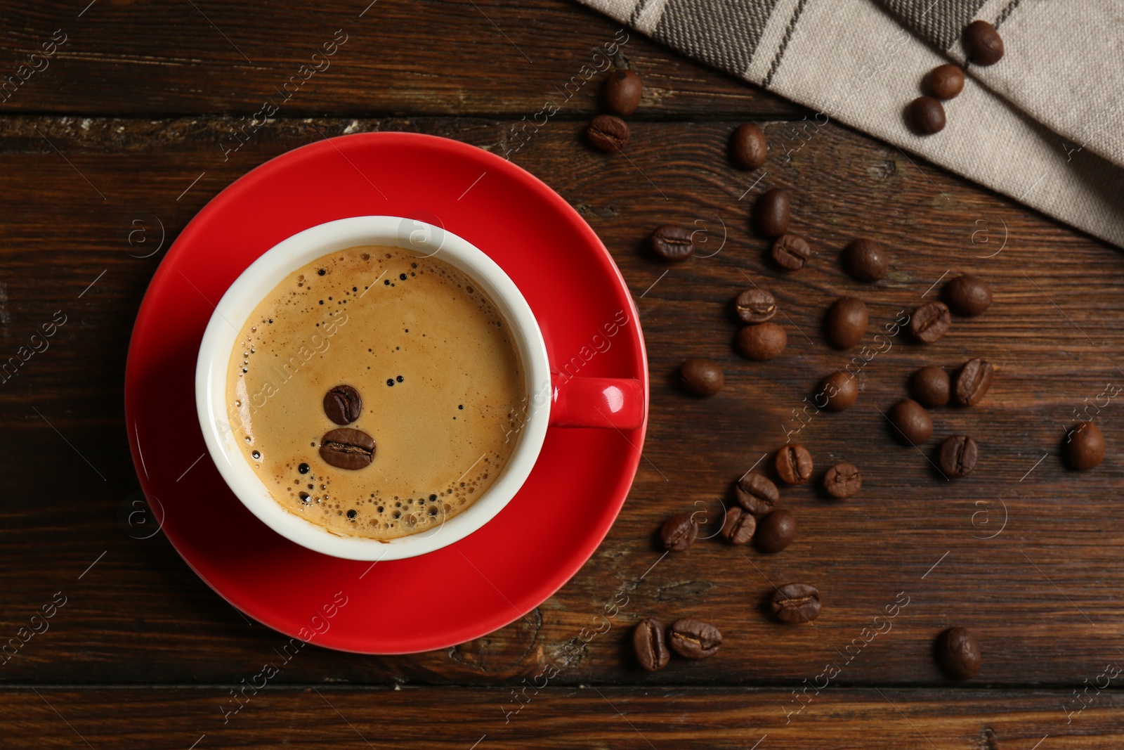 Photo of Red cup with coffee and roasted beans on wooden table, top view. Space for text