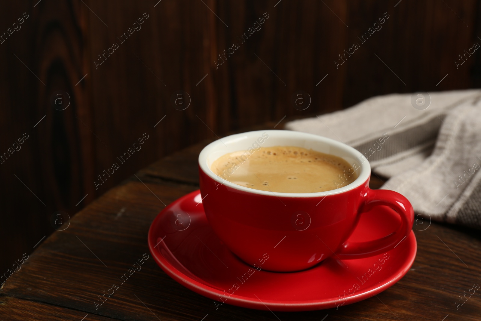 Photo of Red cup with coffee on wooden table, space for text