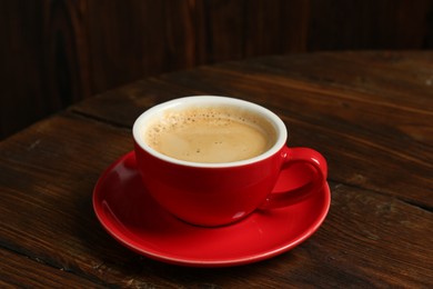 Photo of Red cup with coffee on wooden table