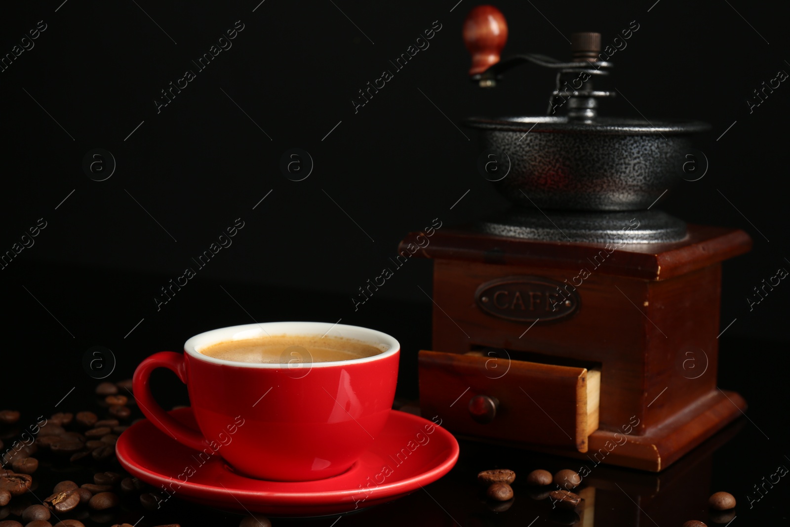 Photo of Red cup with coffee, roasted beans and vintage grinder on black background