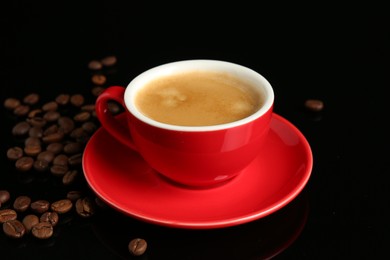 Photo of Red cup with coffee and roasted beans on black background, closeup