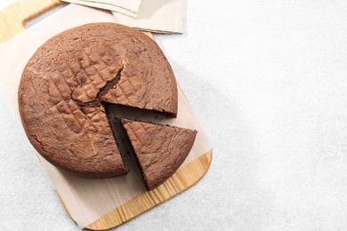 Photo of Cut chocolate sponge cake on light table, top view