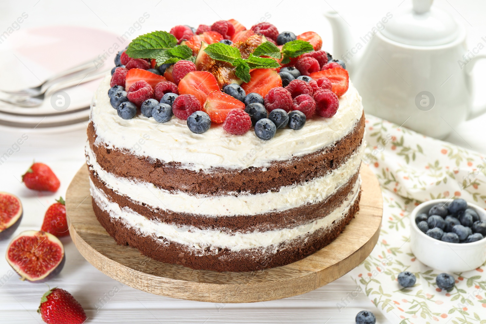 Photo of Delicious chocolate sponge cake with berries served on light table, closeup