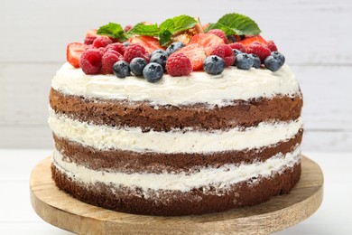 Photo of Delicious chocolate sponge cake with berries on light table, closeup