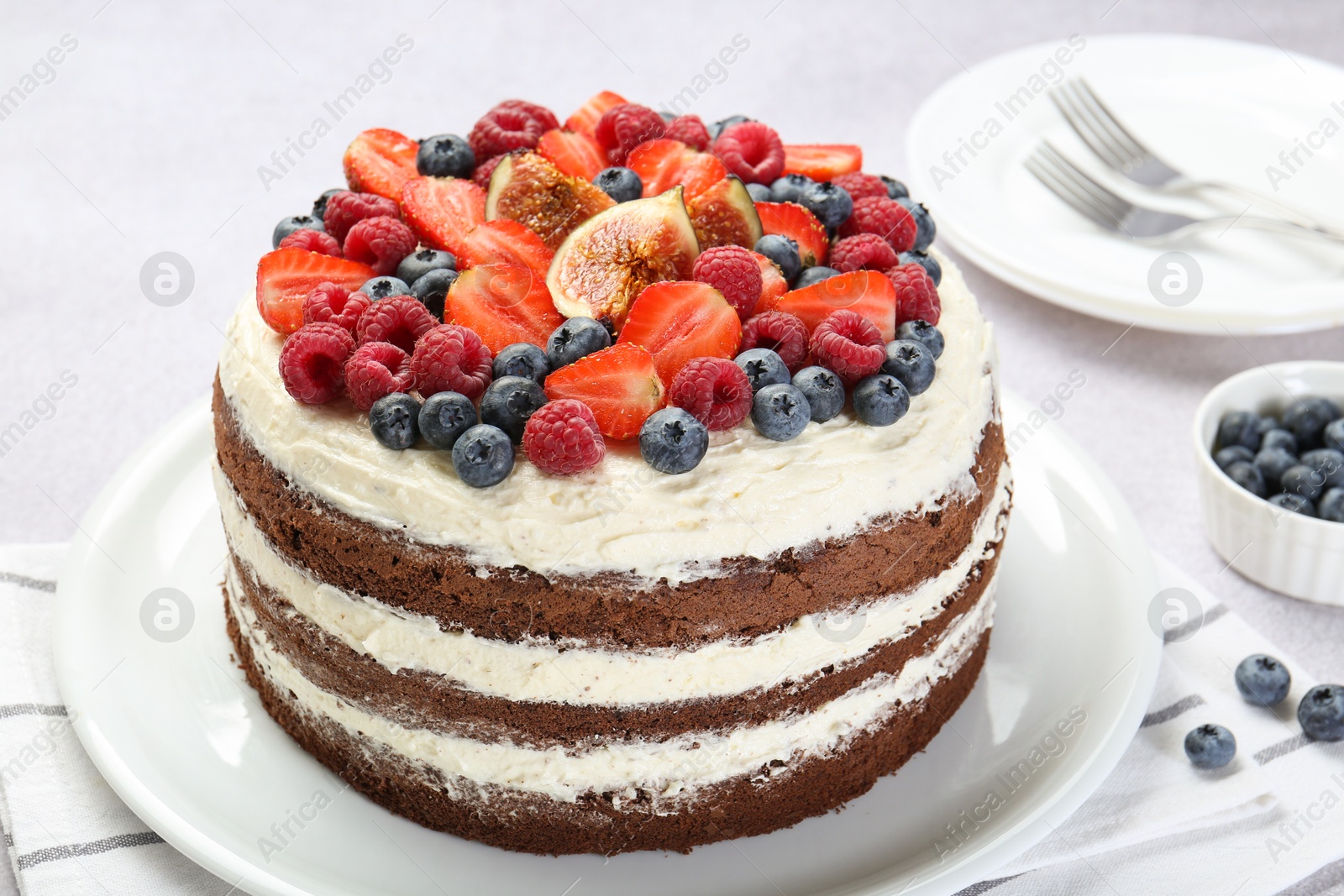 Photo of Delicious chocolate sponge cake with berries served on light table, closeup