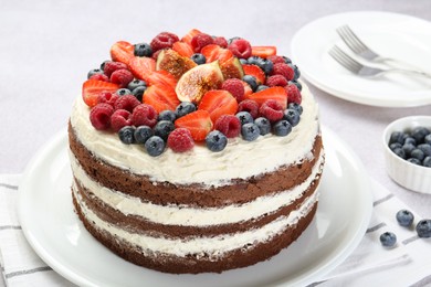 Photo of Delicious chocolate sponge cake with berries served on light table, closeup