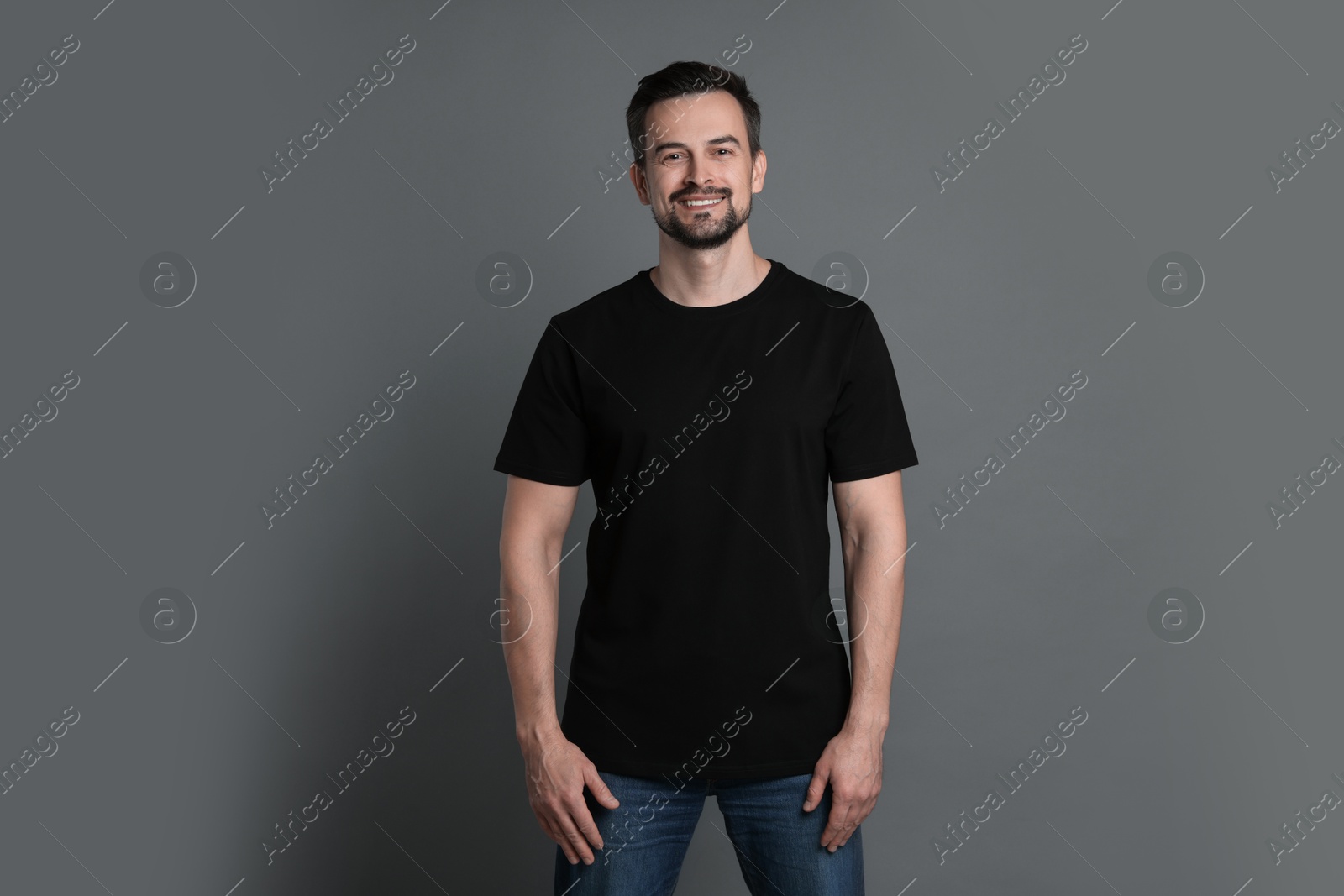 Photo of Man in blank black t-shirt on grey background. Mockup for design