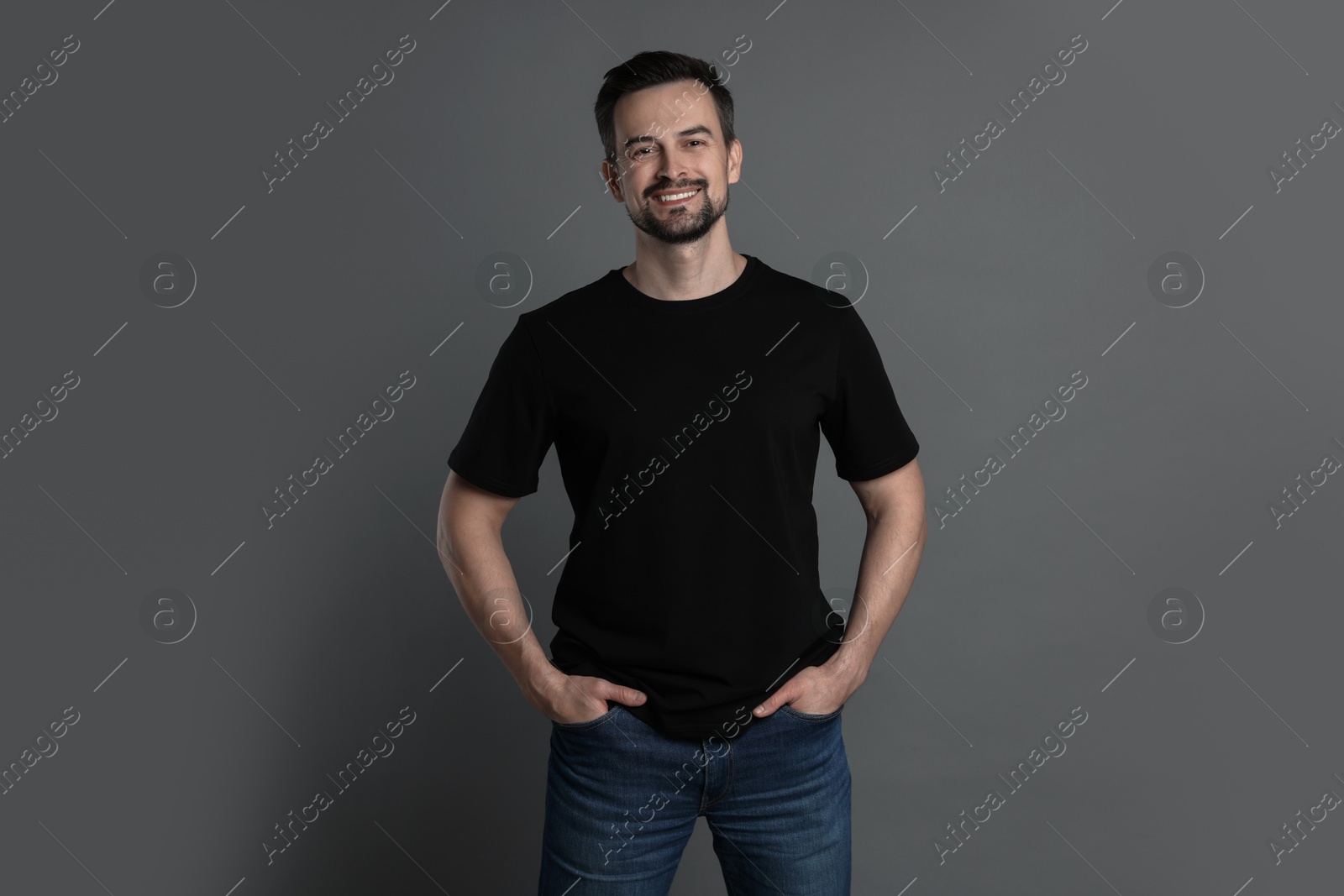 Photo of Man in blank black t-shirt on grey background. Mockup for design