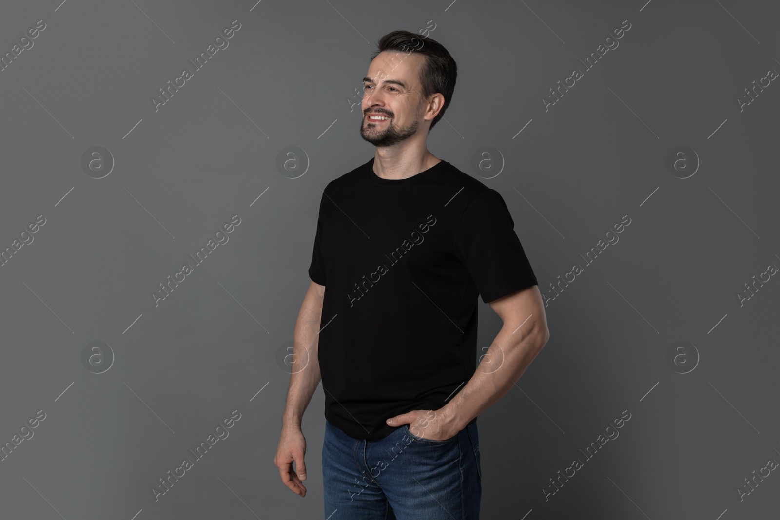 Photo of Man in blank black t-shirt on grey background. Mockup for design