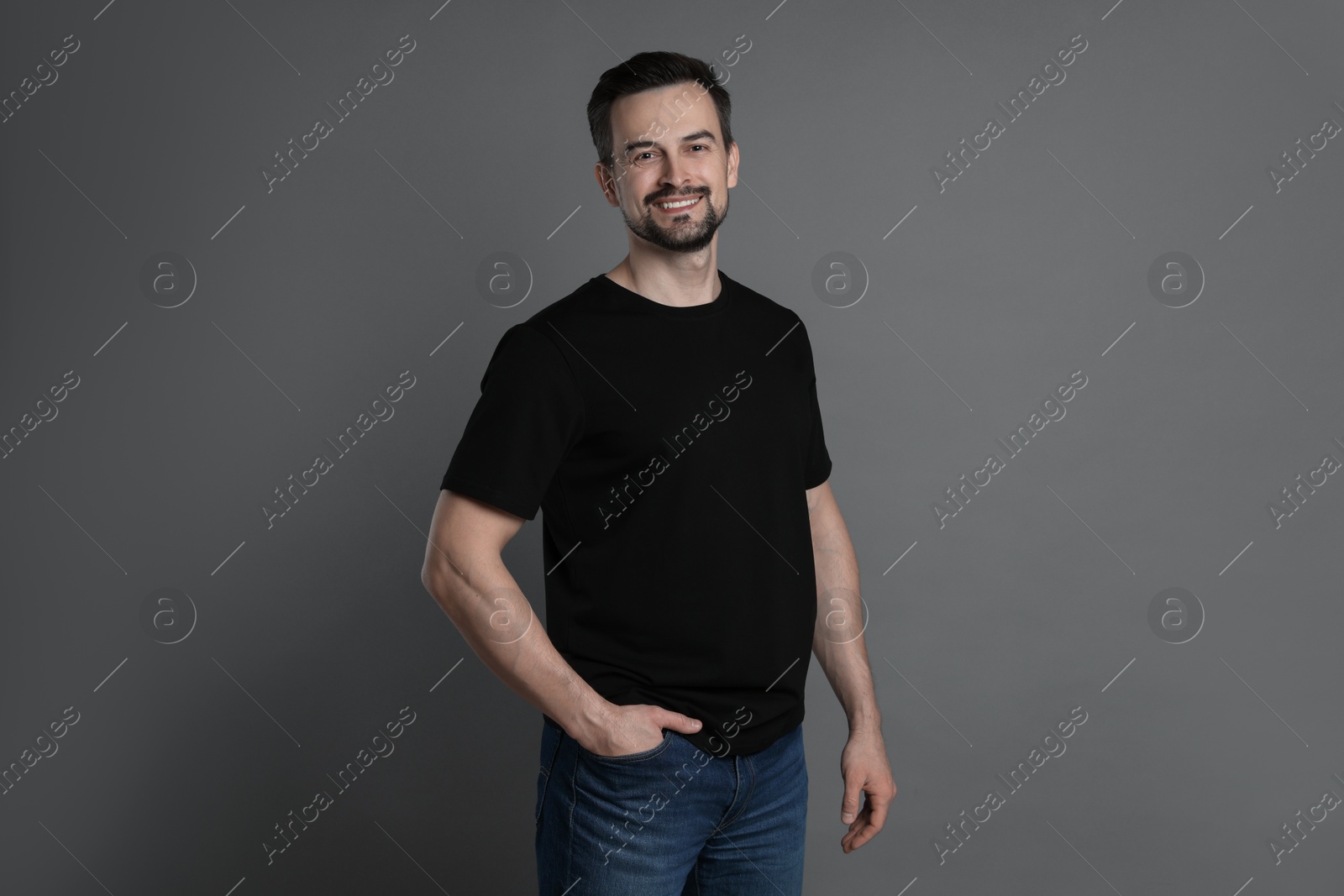 Photo of Man in blank black t-shirt on grey background. Mockup for design