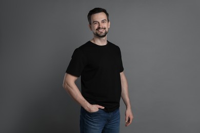 Photo of Man in blank black t-shirt on grey background. Mockup for design