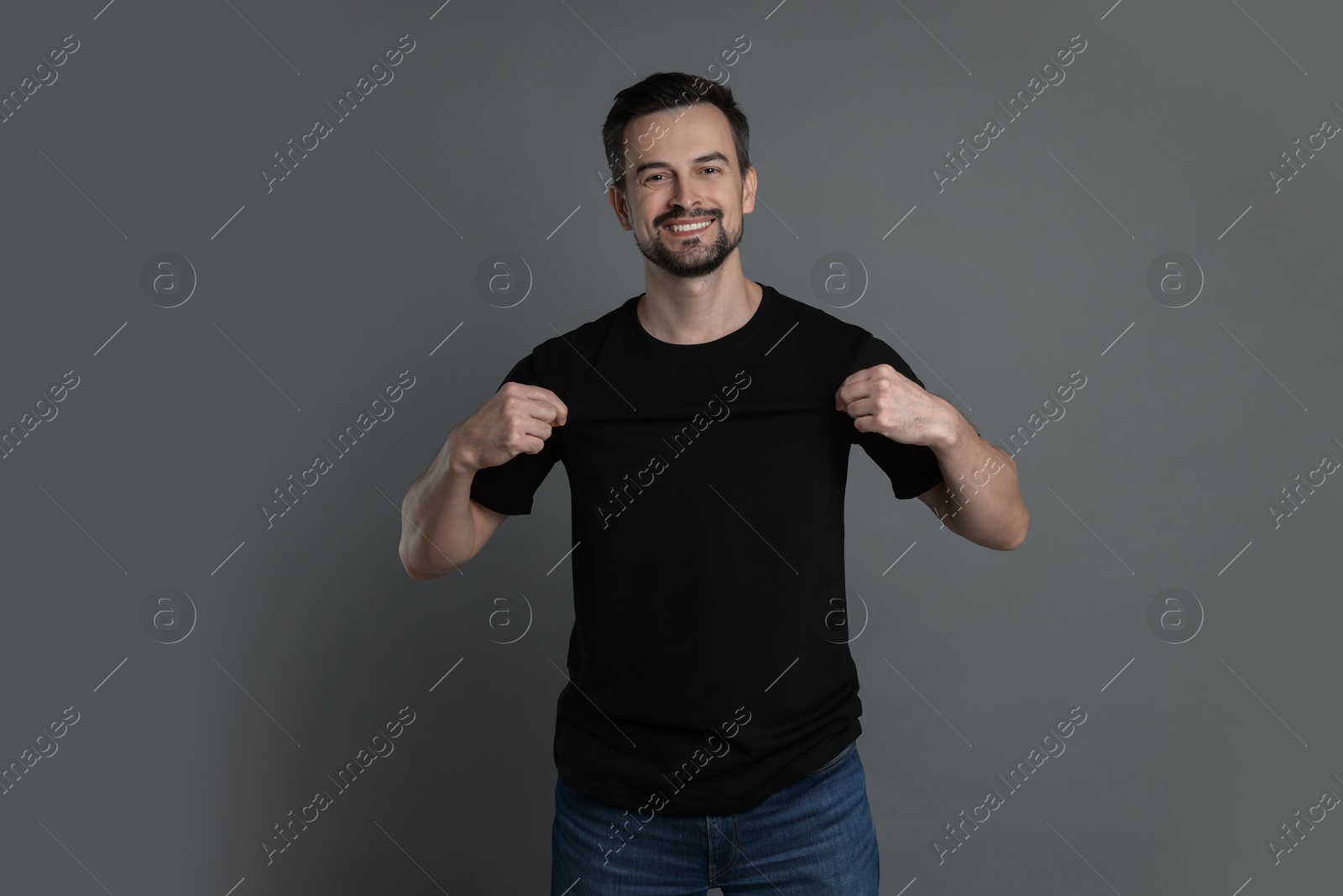 Photo of Man in blank black t-shirt on grey background. Mockup for design