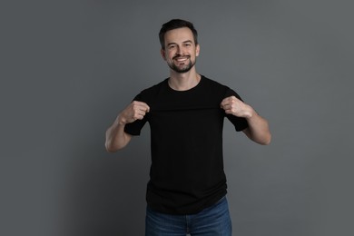 Photo of Man in blank black t-shirt on grey background. Mockup for design