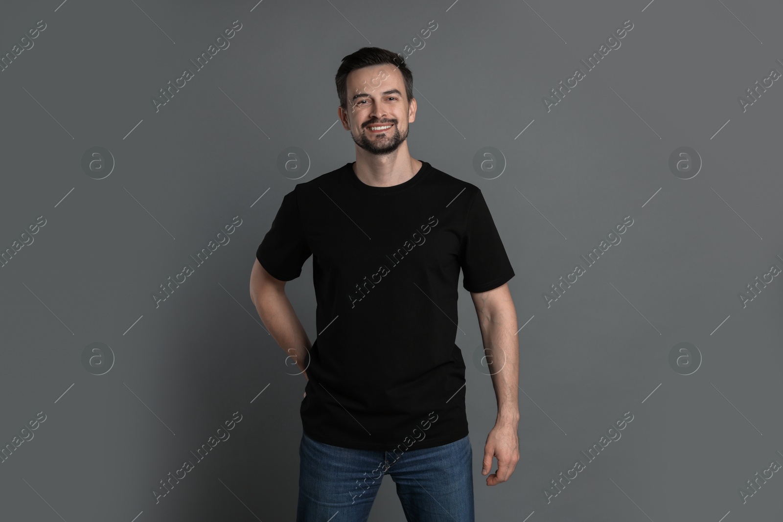 Photo of Man in blank black t-shirt on grey background. Mockup for design