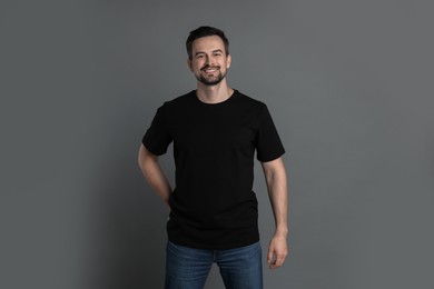 Photo of Man in blank black t-shirt on grey background. Mockup for design