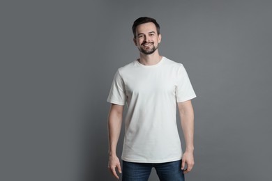 Photo of Man in blank white t-shirt on grey background. Mockup for design