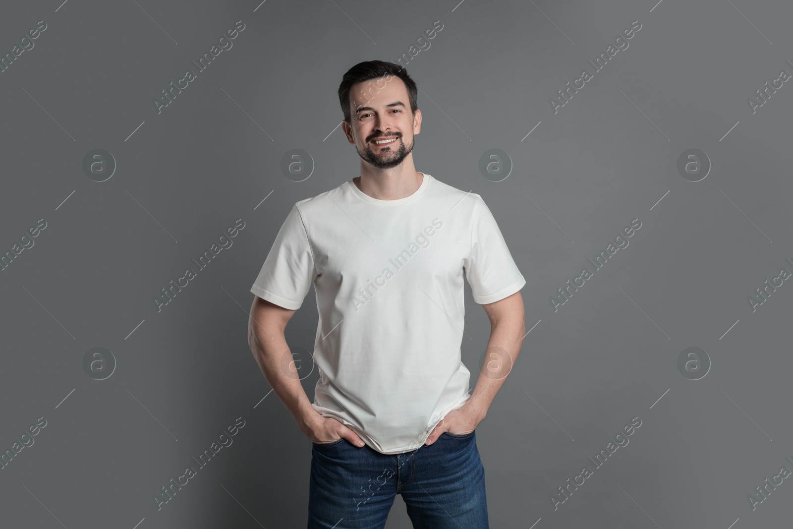 Photo of Man in blank white t-shirt on grey background. Mockup for design