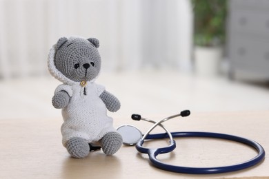 Pediatrics concept. Toy bear with stethoscope on table indoors, space for text