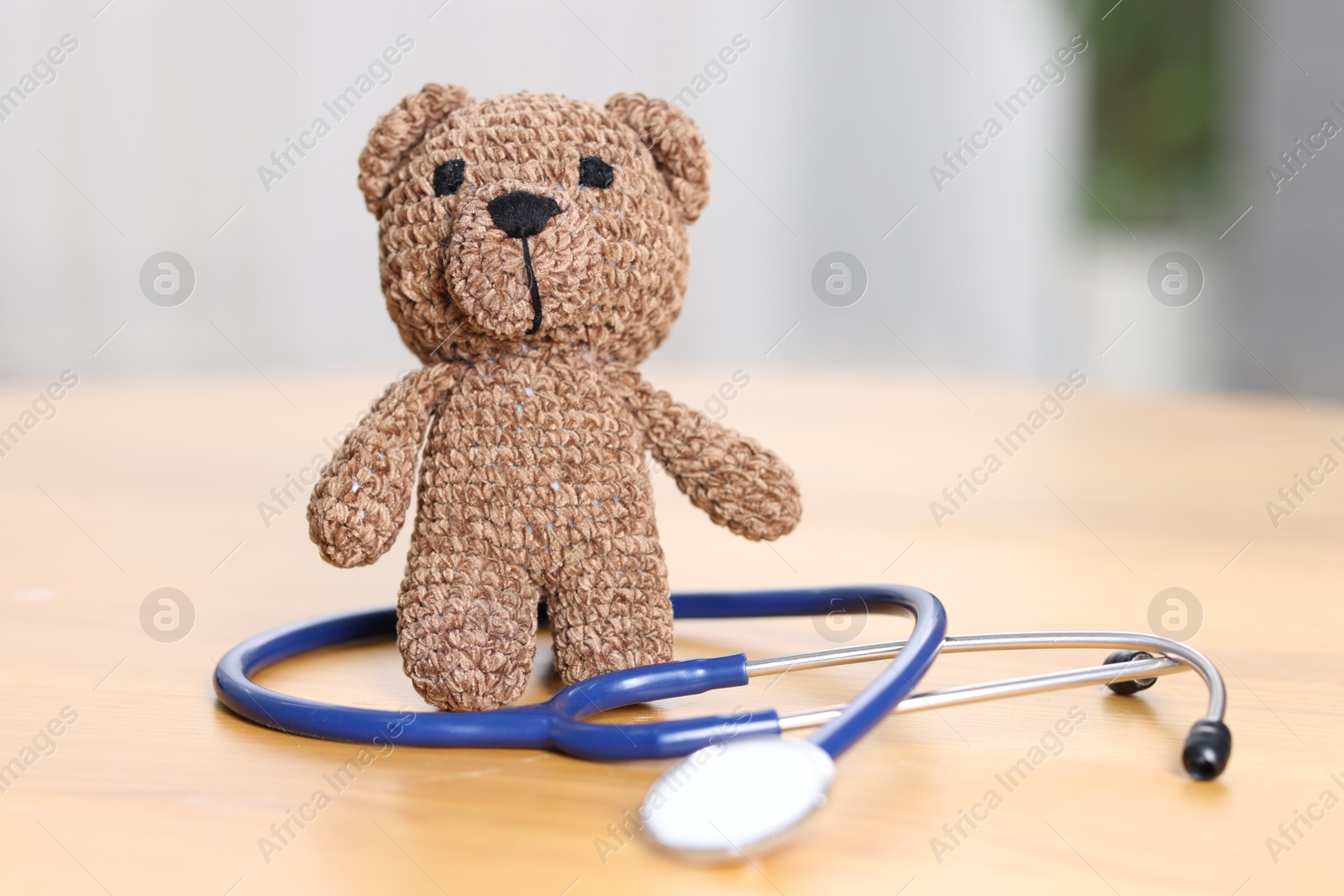 Photo of Pediatrics concept. Toy bear with stethoscope on table indoors