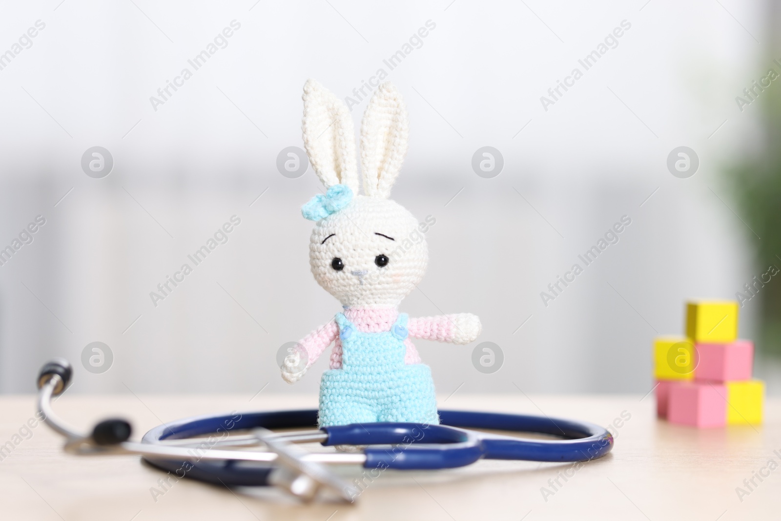 Photo of Pediatrics concept. Toy bunny with stethoscope on table indoors