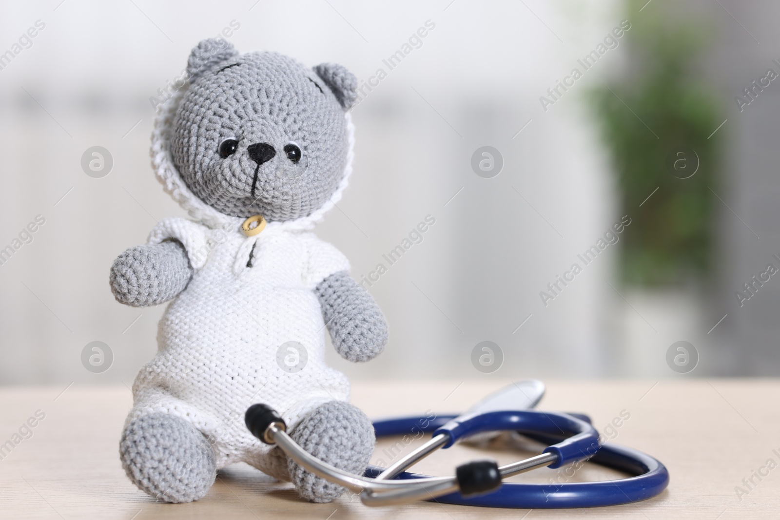 Photo of Pediatrics concept. Toy bear with stethoscope on table indoors, space for text