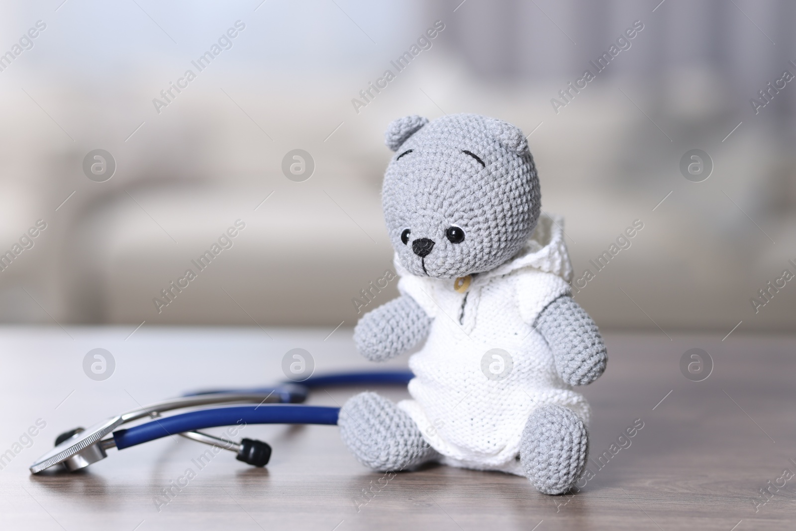 Photo of Pediatrics concept. Toy bear with stethoscope on wooden table indoors, space for text