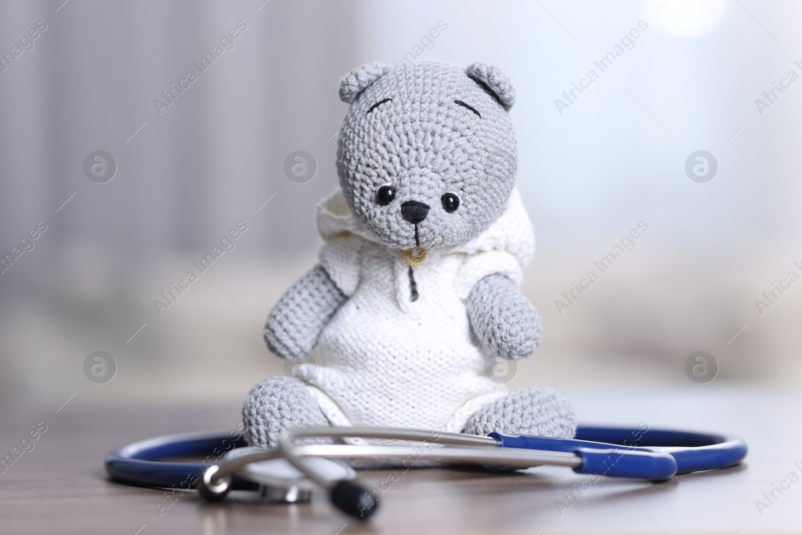 Photo of Pediatrics concept. Toy bear with stethoscope on table indoors