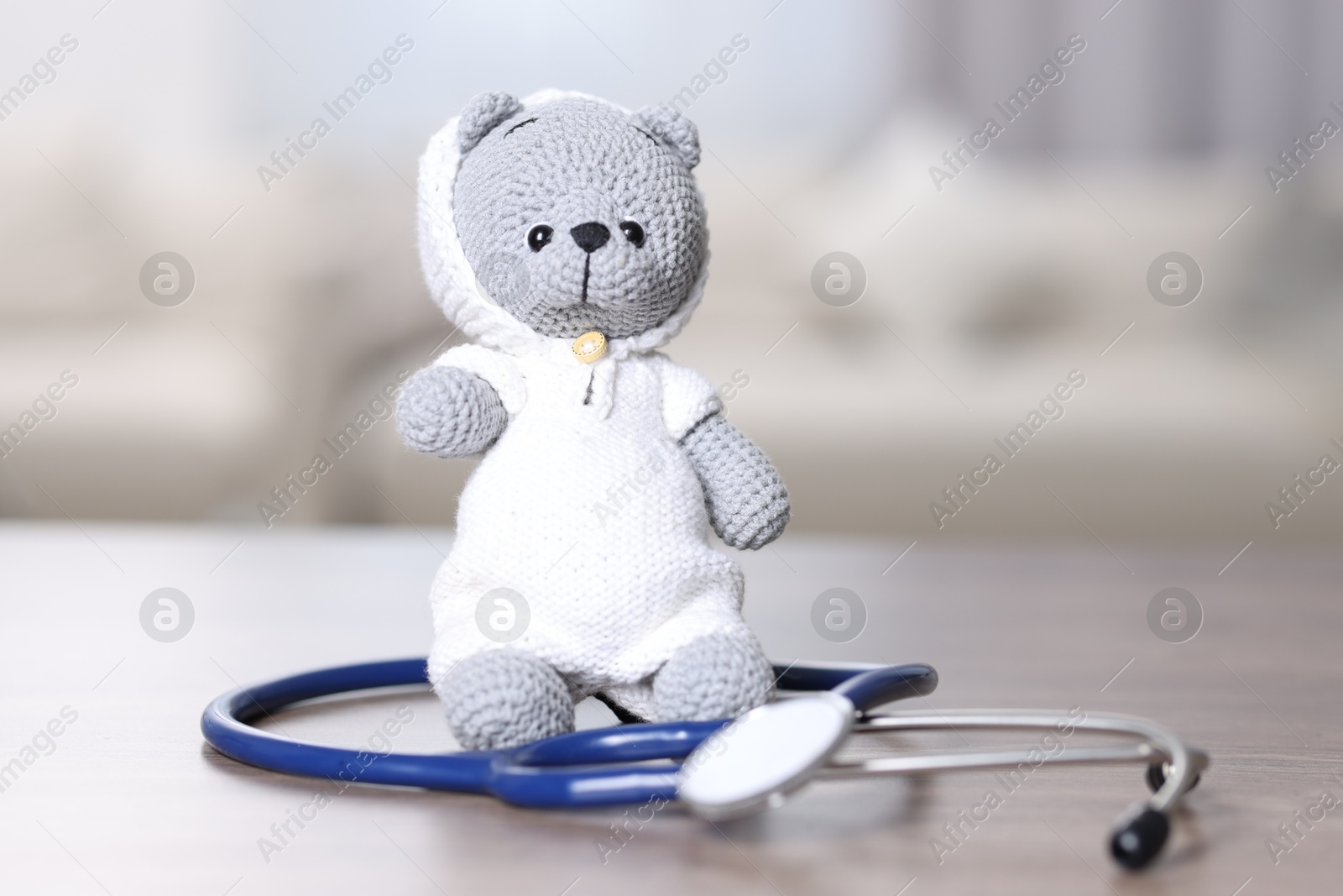 Photo of Pediatrics concept. Toy bear with stethoscope on table indoors