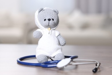 Photo of Pediatrics concept. Toy bear with stethoscope on table indoors