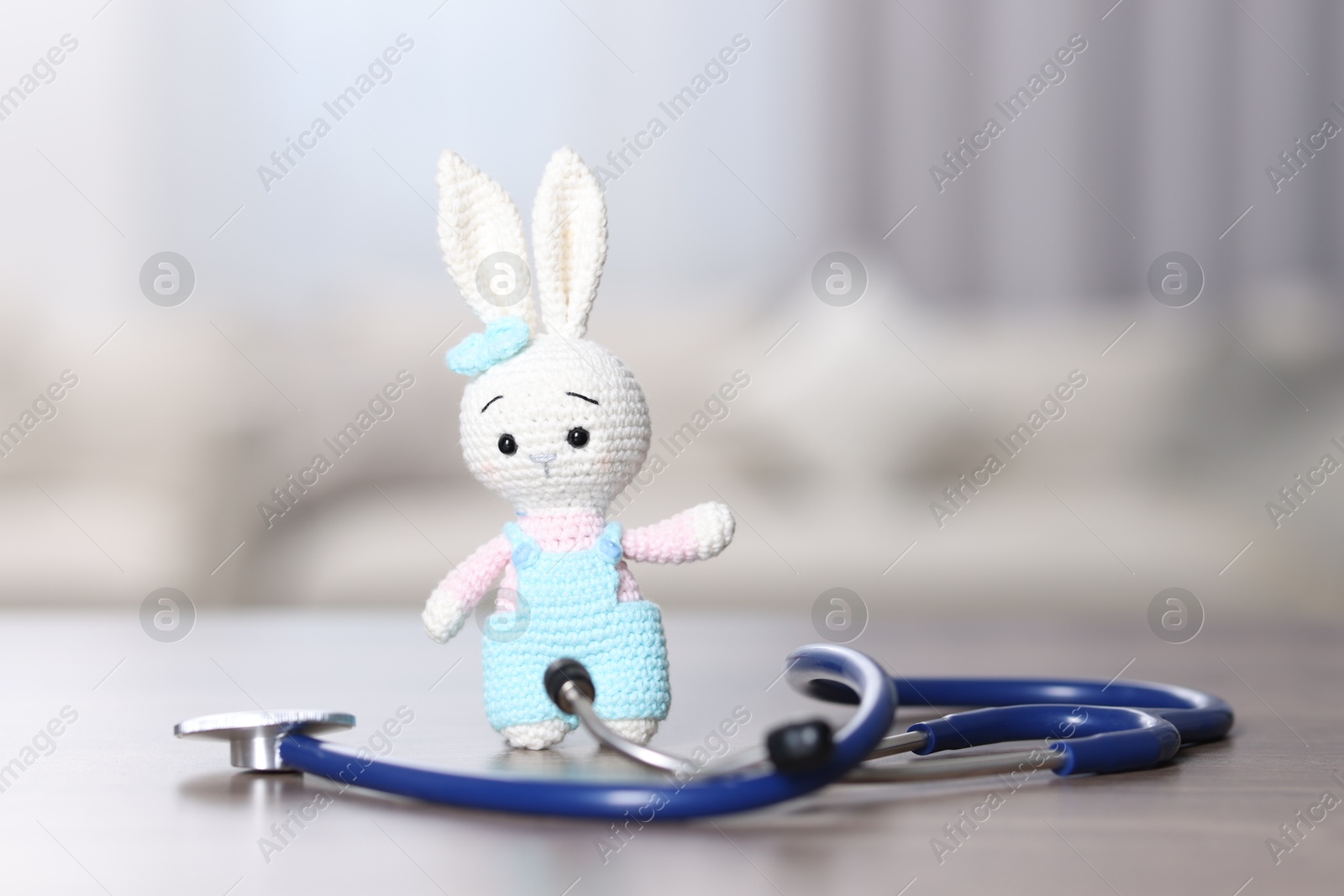 Photo of Pediatrics concept. Toy bunny with stethoscope on table indoors