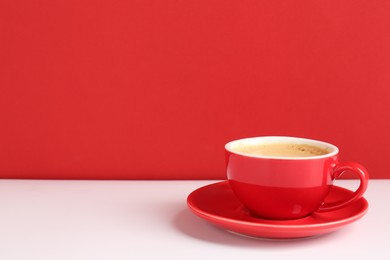 Photo of Red cup with coffee on white table. Space for text