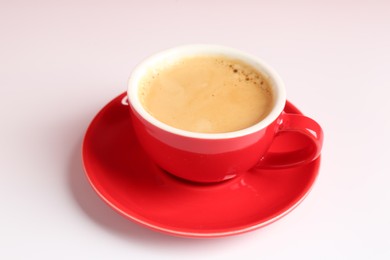 Photo of Red cup with coffee on white table, closeup