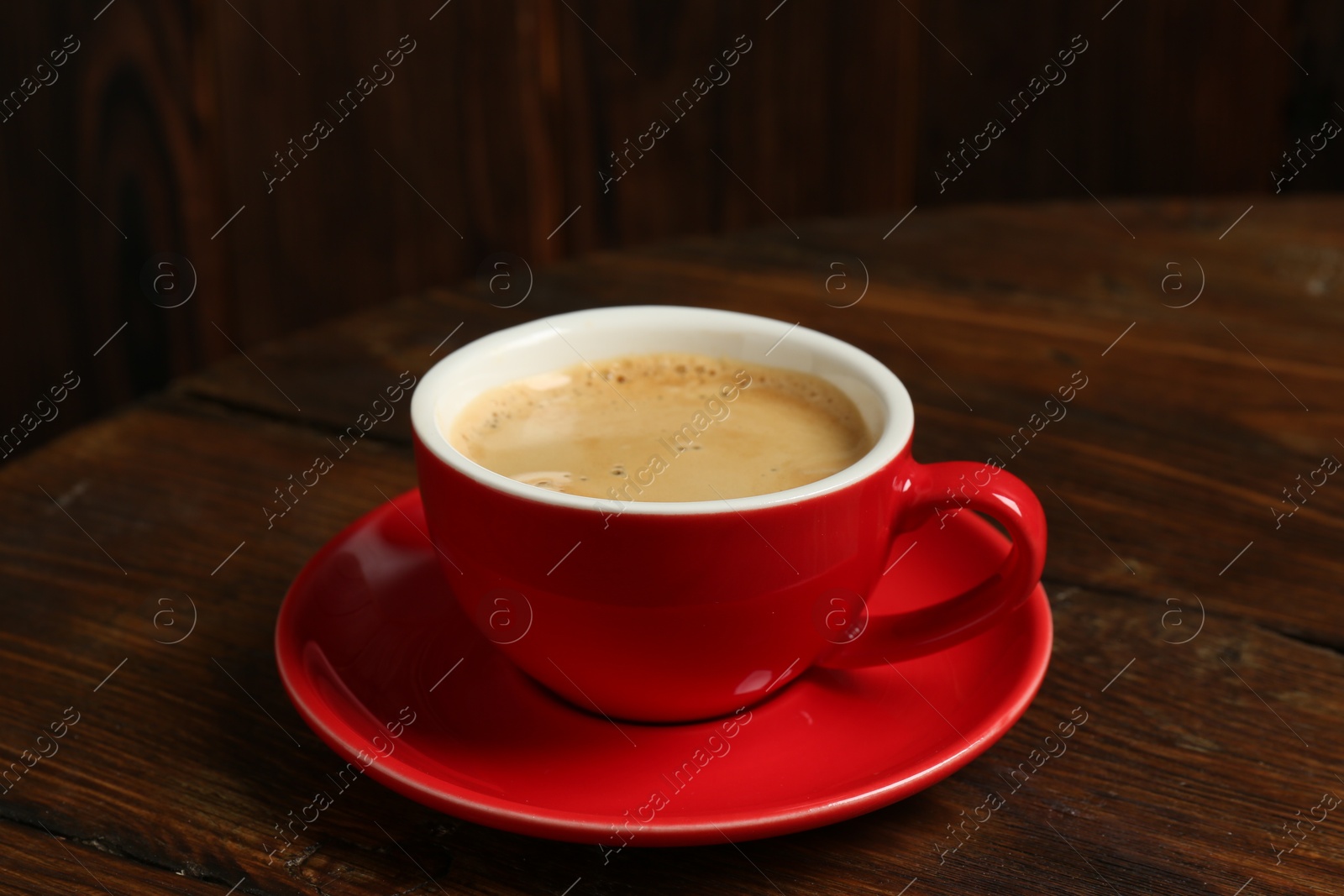 Photo of Red cup with coffee on wooden table, closeup