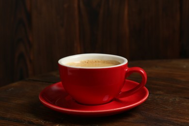 Photo of Red cup with coffee on wooden table, closeup