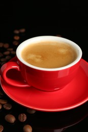 Photo of Red cup with coffee and roasted beans on black background, closeup