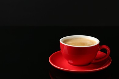 Red cup with coffee on black background, space for text