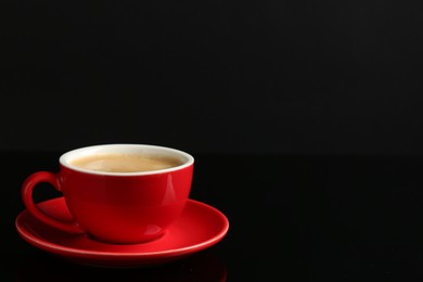 Photo of Red cup with coffee on black background, space for text