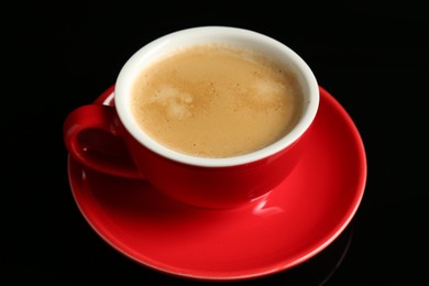 Photo of Red cup with coffee on black background, closeup