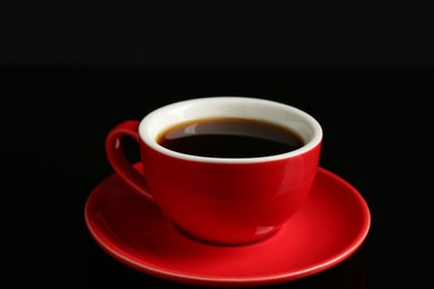 Photo of Red cup with coffee on black background, closeup