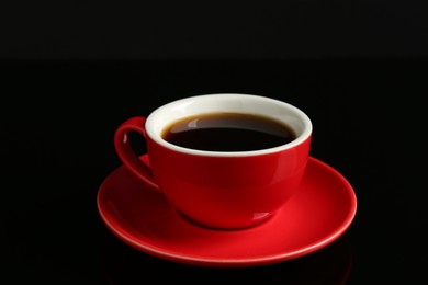 Photo of Red cup with coffee on black background, closeup