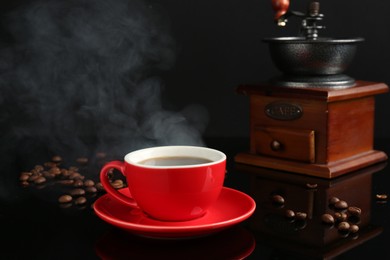 Photo of Red cup with coffee, vintage grinder and roasted beans on black background