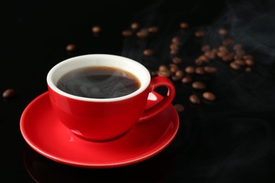 Photo of Red cup with coffee and roasted beans on black background, closeup. Space for text