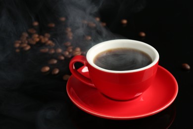 Photo of Red cup with coffee and roasted beans on black background, closeup