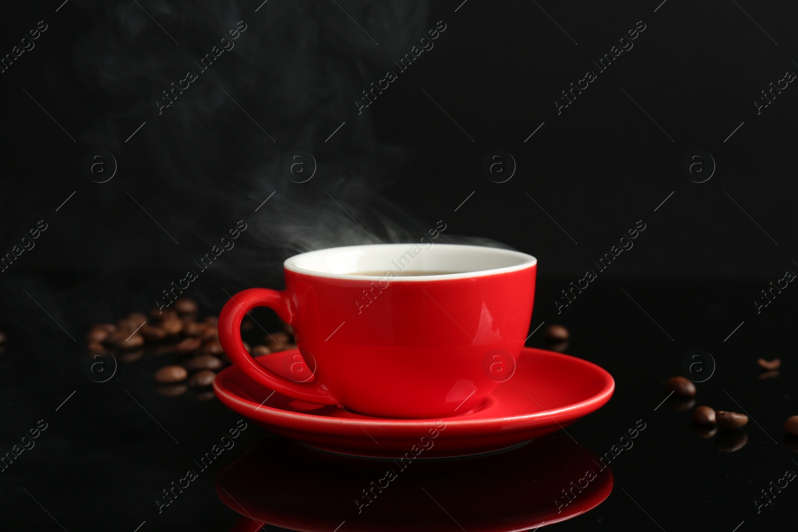 Photo of Red cup with coffee and roasted beans on black background