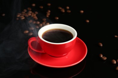 Photo of Red cup with coffee and roasted beans on black background