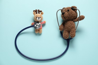 Photo of Pediatrics concept. Toy bear and deer with stethoscope on light blue background, flat lay