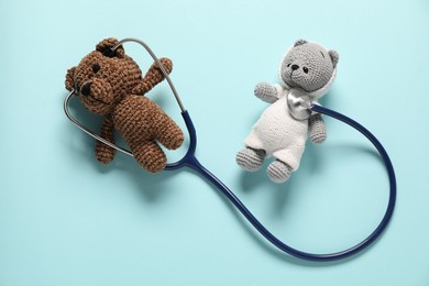 Photo of Pediatrics concept. Toy bears with stethoscope on light blue background, flat lay